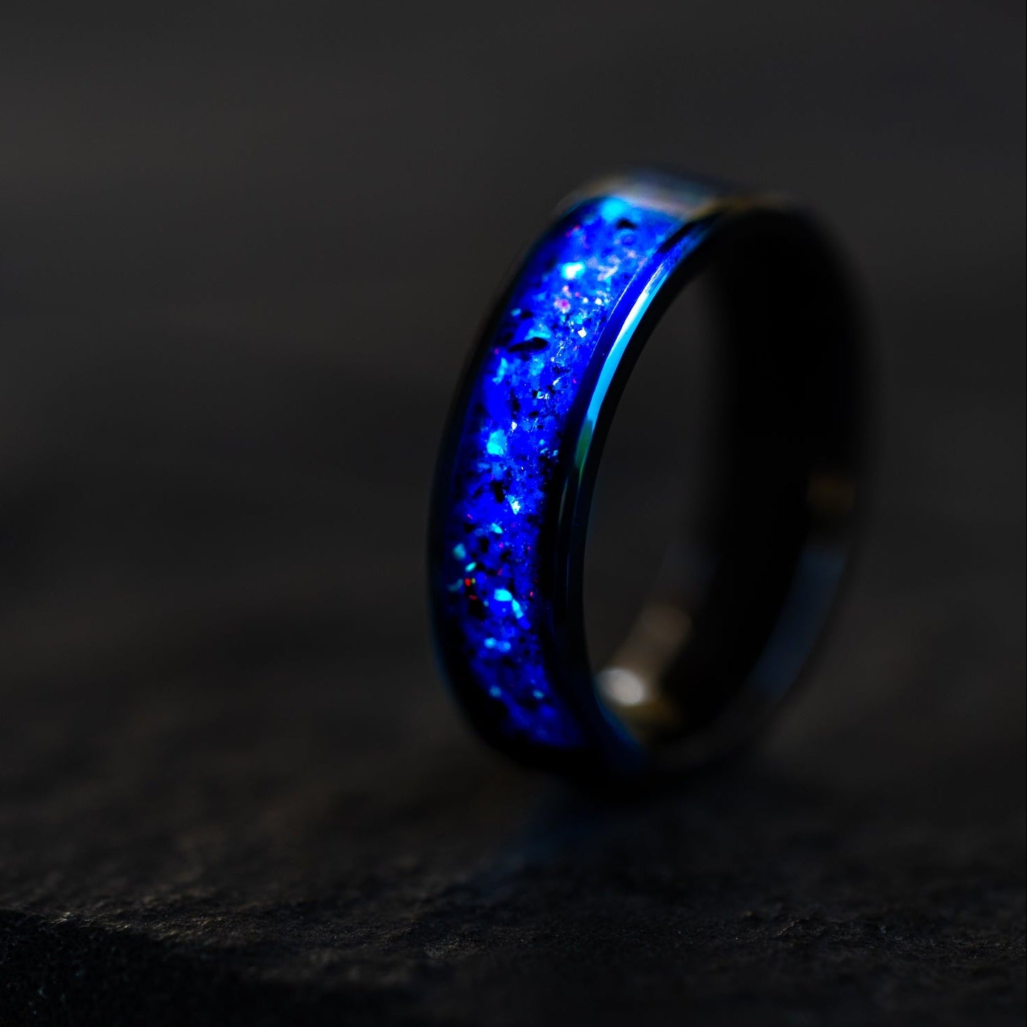 Close up of genuine Megalodon shark tooth and meteorite shavings suspended in blue and purple midnight opal inlay on ceramic ring