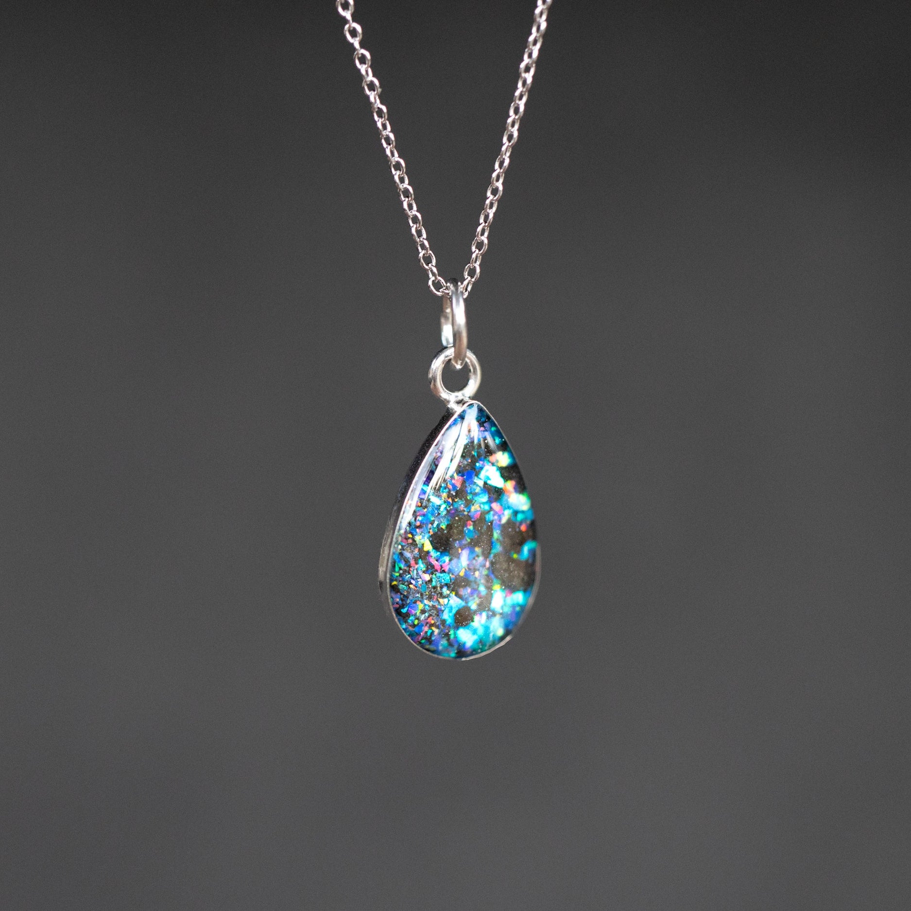 Close-up of the Megalodon Tide real megalodon tooth necklace showing fossilized shark tooth fragments set with vivid blue and purple opals