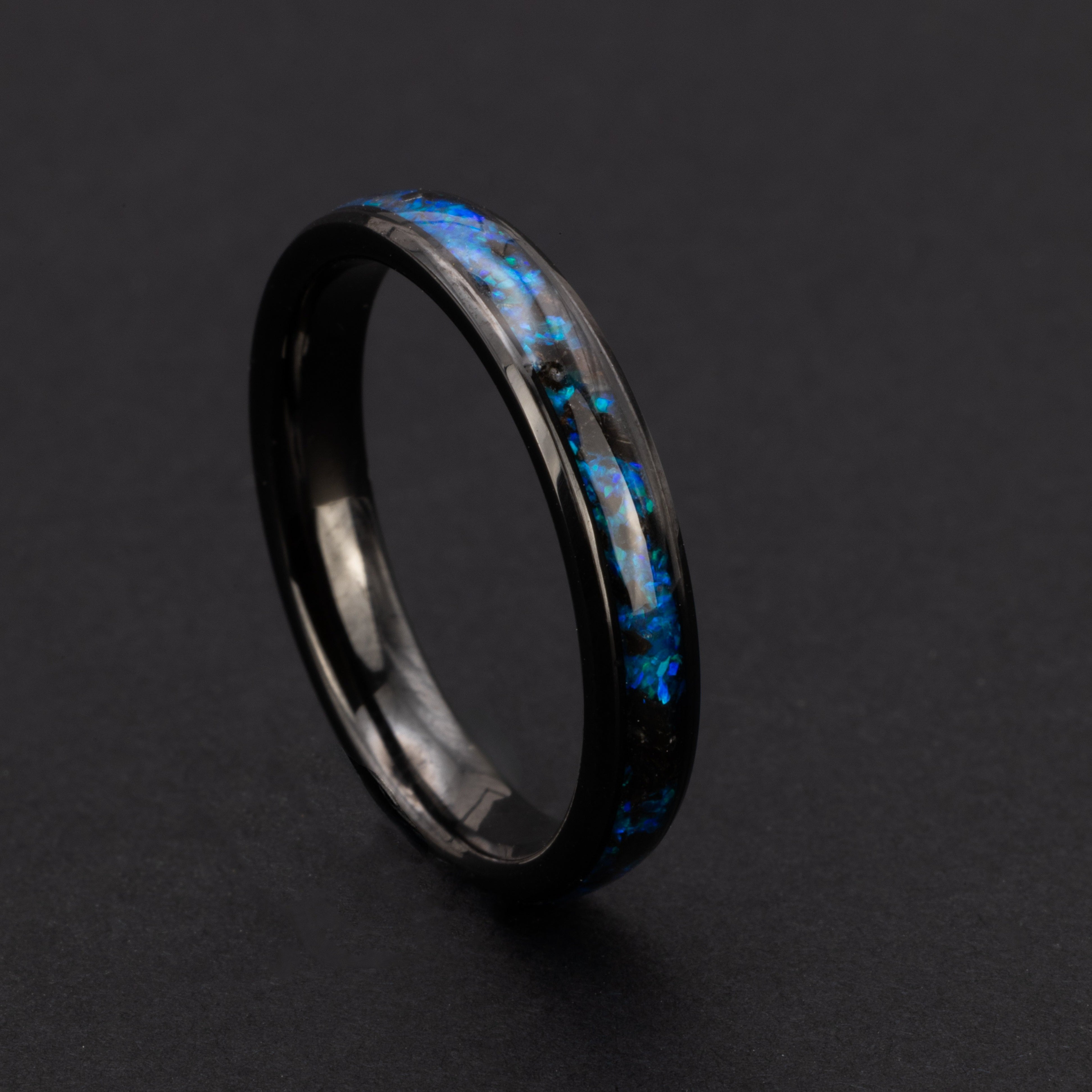 Close up of genuine Megalodon shark tooth fragments suspended in blue opal inlay on slim 4mm beveled black ceramic ring