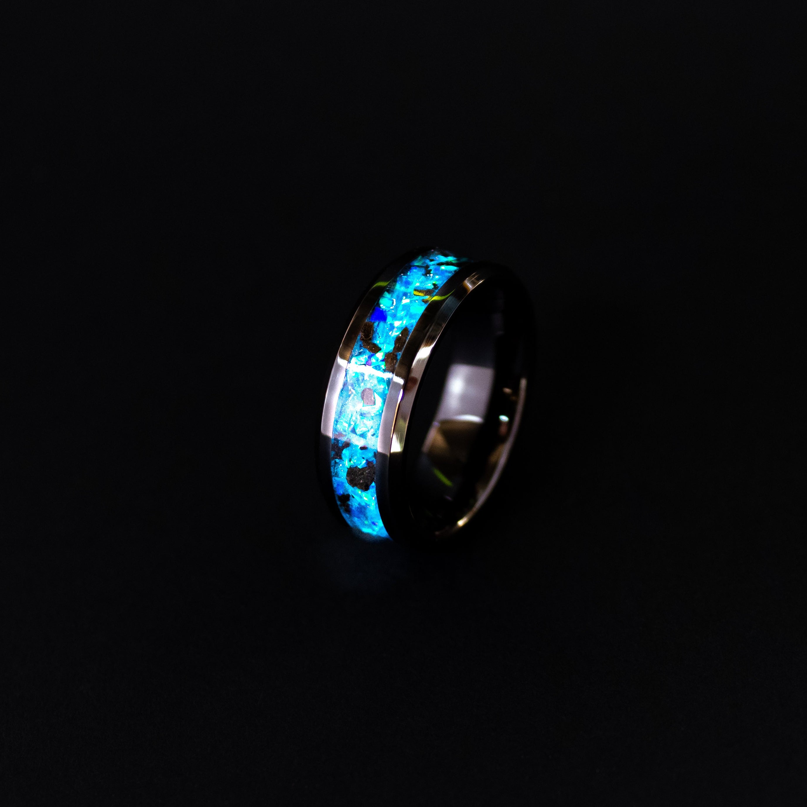 Close up of genuine Megalodon shark tooth fragments suspended in blue opal inlay on beveled black ceramic ring