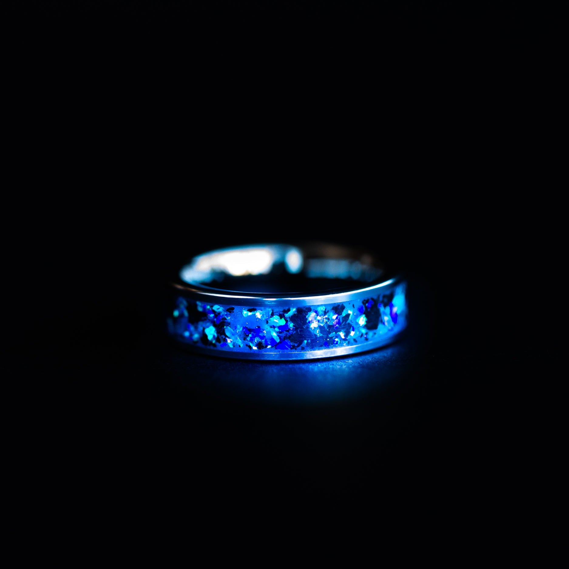 Close up of genuine Megalodon shark tooth fossil suspended in blue opal inlay on 6mm wide channel tungsten ring