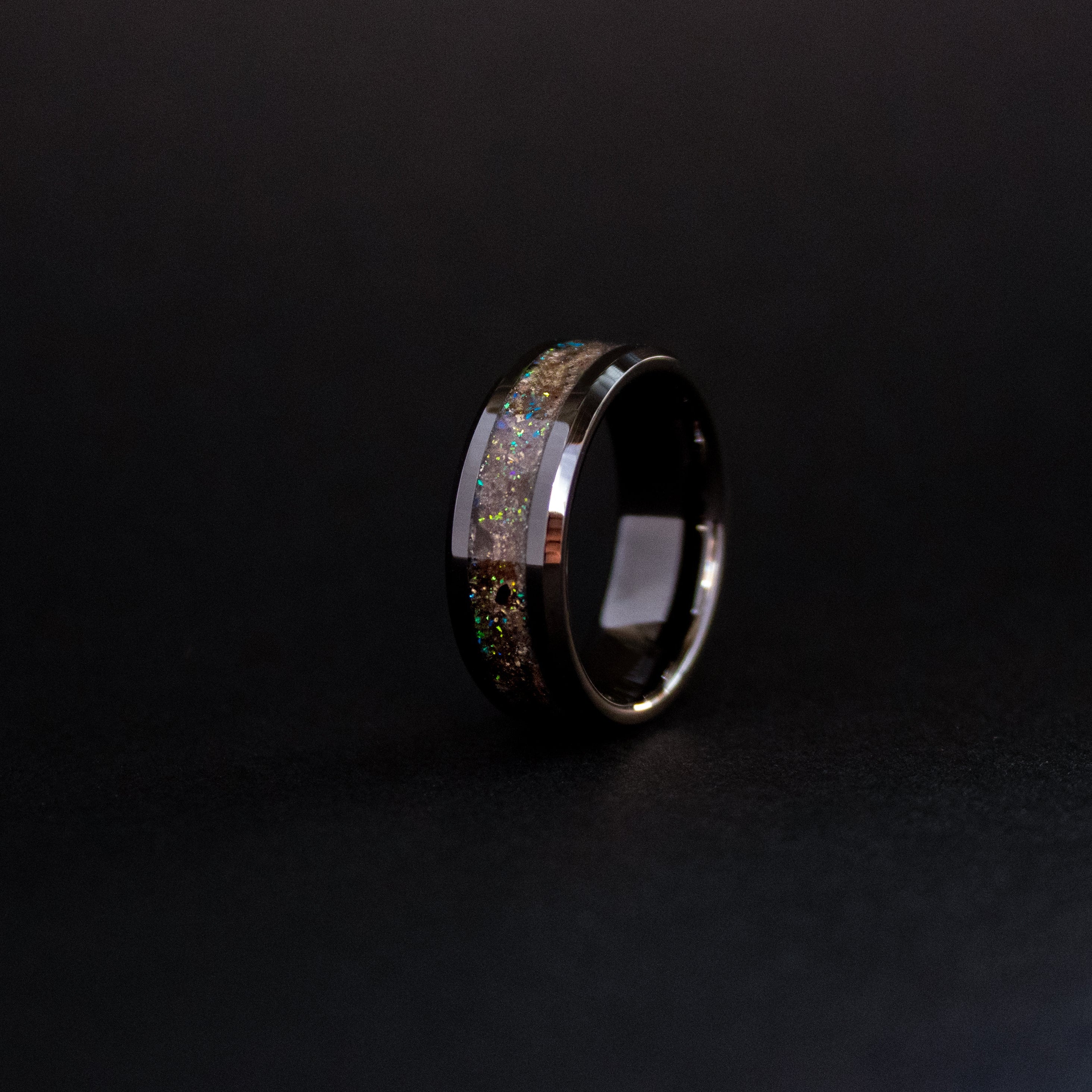 Close up of genuine Megalodon shark tooth and Campo del Cielo meteorite shavings suspended in blue and green opal inlay with iridescent flakes on beveled ceramic ring