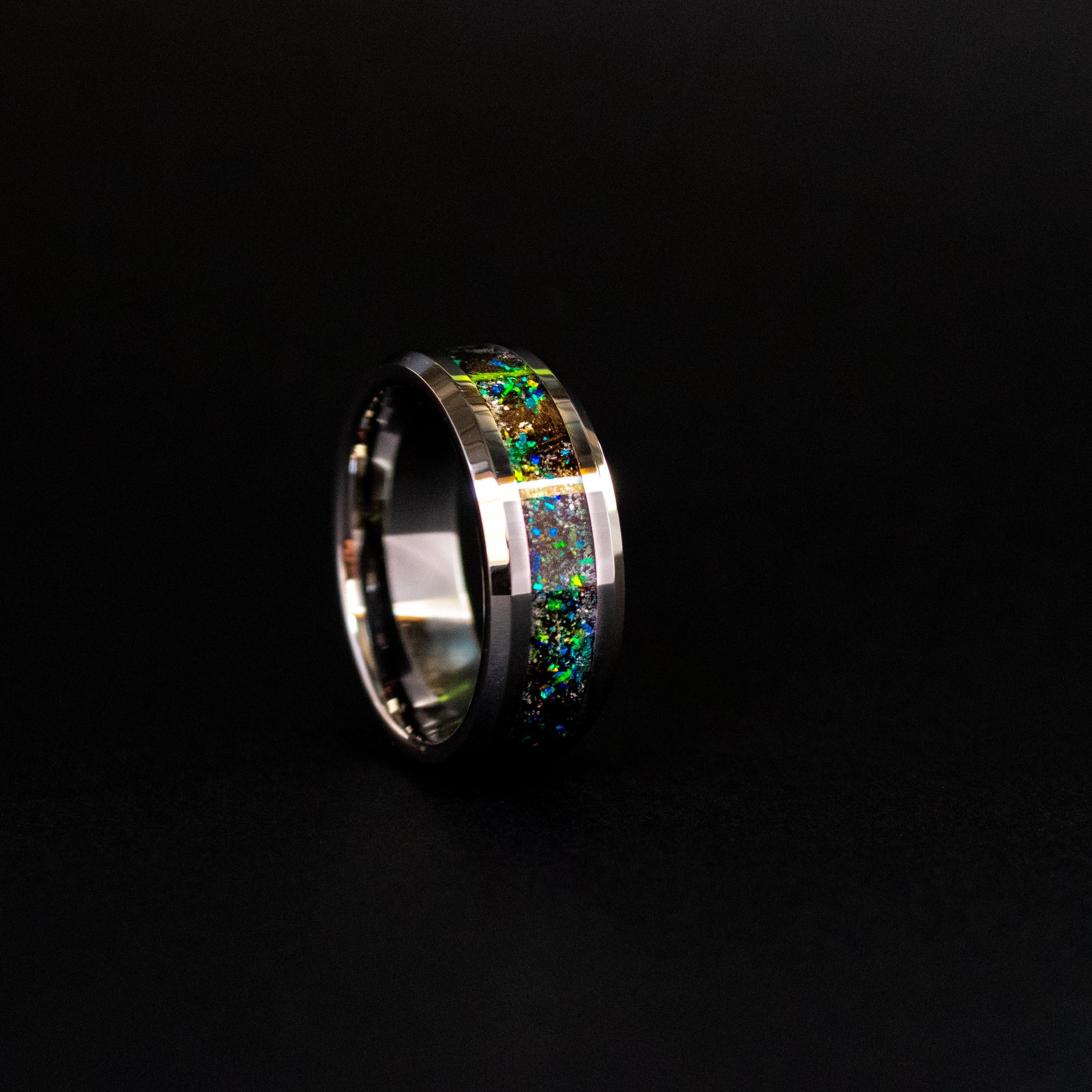 Close up of genuine Megalodon shark tooth and Campo del Cielo meteorite shavings suspended in blue and green opal inlay with iridescent flakes on beveled tungsten ring
