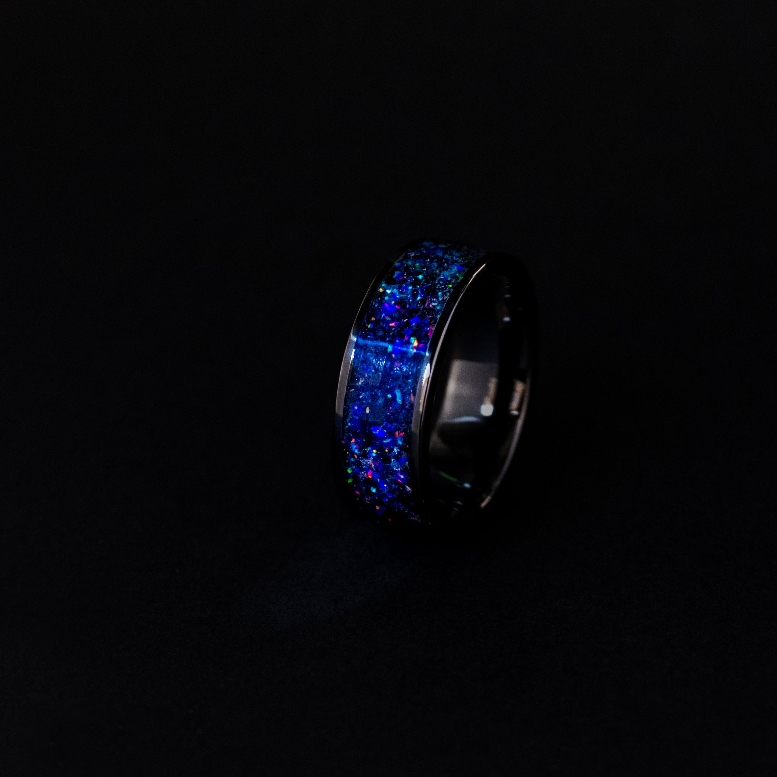 Close up of genuine Megalodon shark tooth and Campo del Cielo meteorite shavings suspended in midnight opal inlay on wide channel black ceramic ring