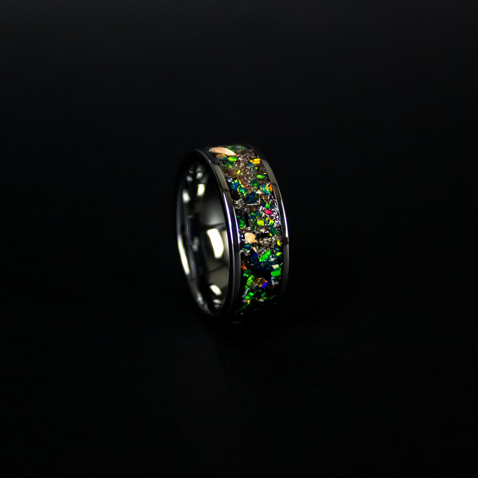 Close up of genuine Mosasaur bone, Dinosaur Gembone, and Campo del Cielo meteorite shavings suspended in dark green opal inlay on wide channel tungsten ring