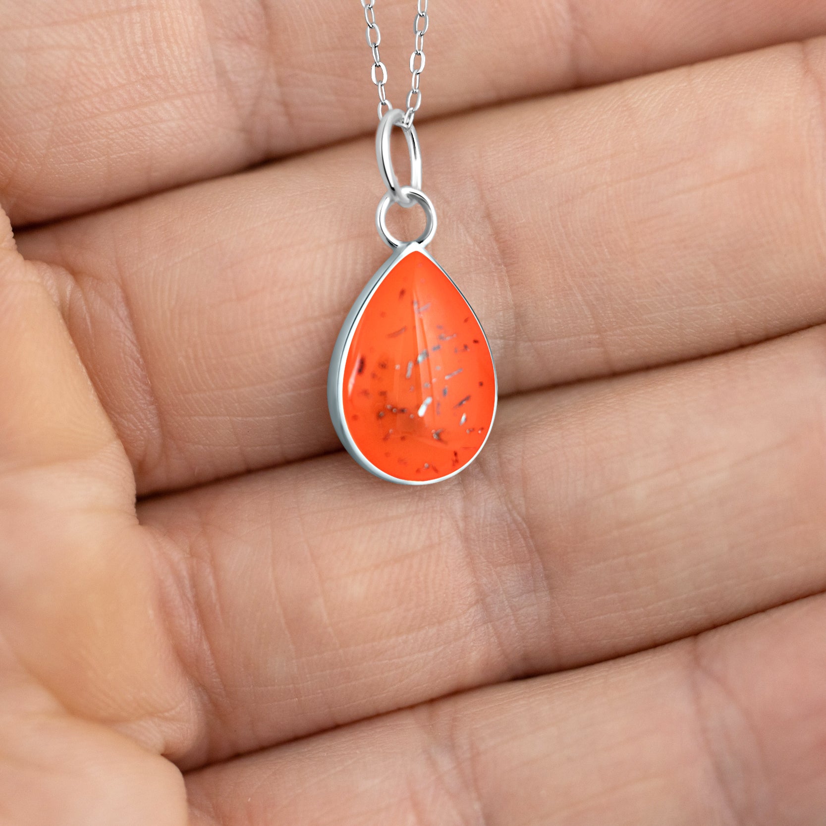 Close-up of the Orange Drop pendant showing authentic Campo Del Cielo meteorite fragments set in orange resin