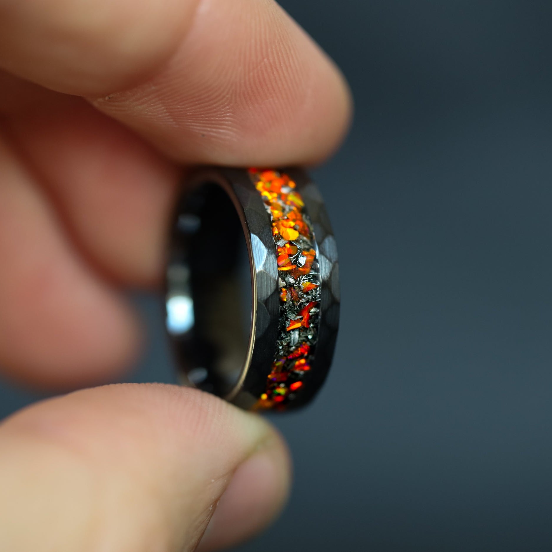 hammered black ceramic wedding band featuring celestial meteorite fragments and magma orange glow.