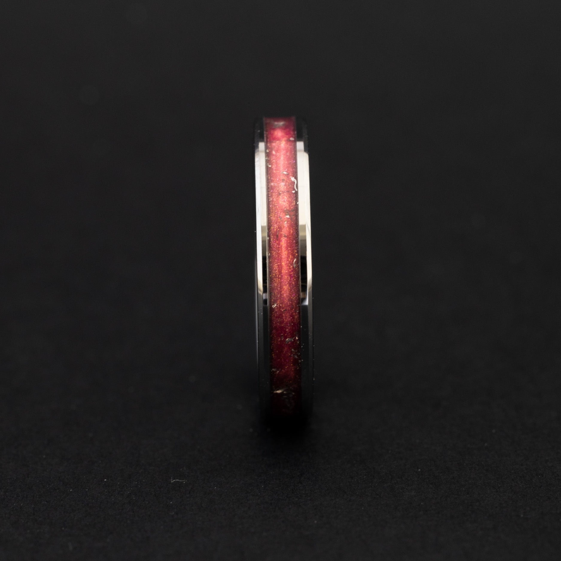 Close up of Campo del Cielo meteorite shavings in a metallic pink and crimson 4mm tungsten ring.