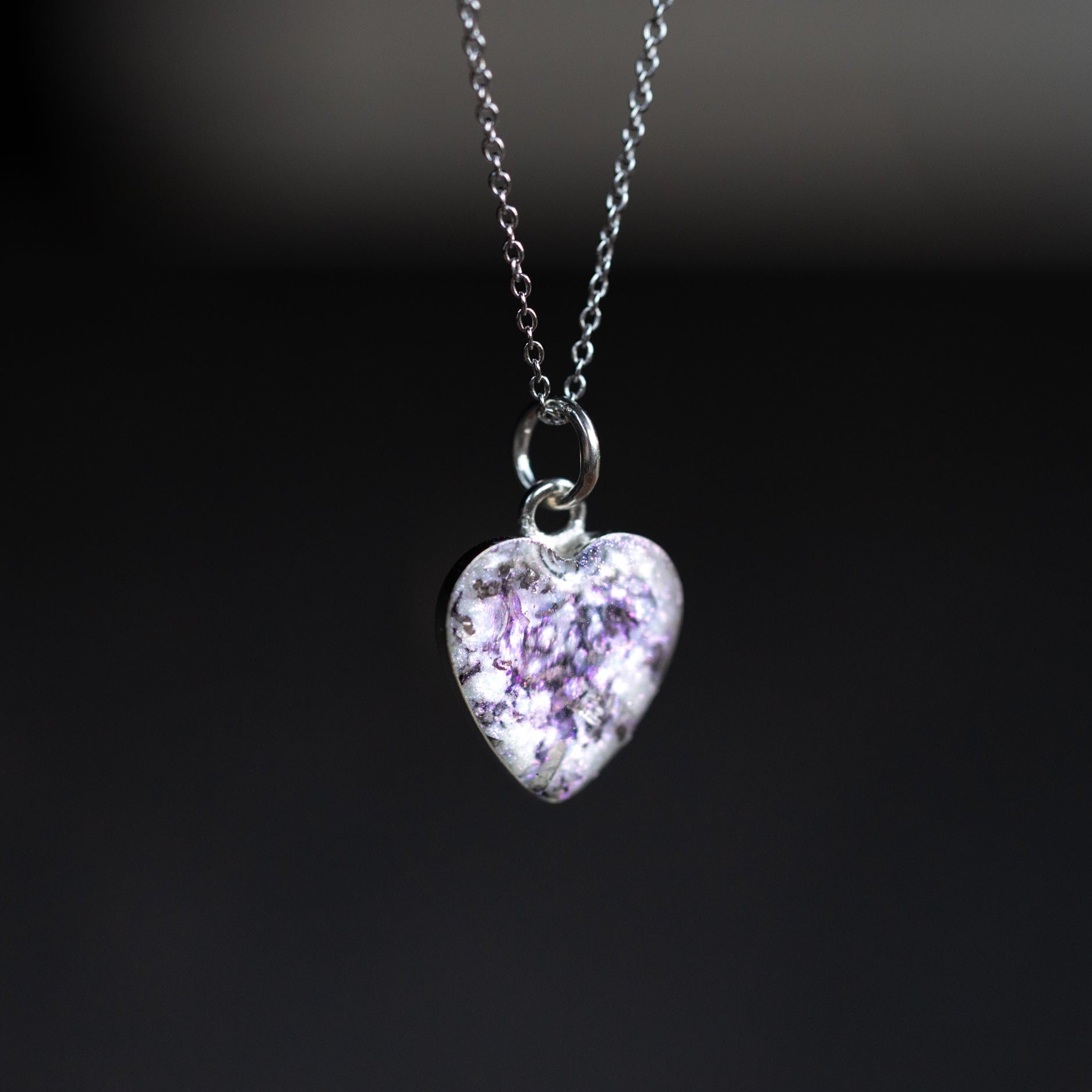 Close-up of the Pink Pearl iridescent heart necklace showing Campo Del Cielo iron meteorite fragments set in pearl-toned white resin with a soft pink shimmer
