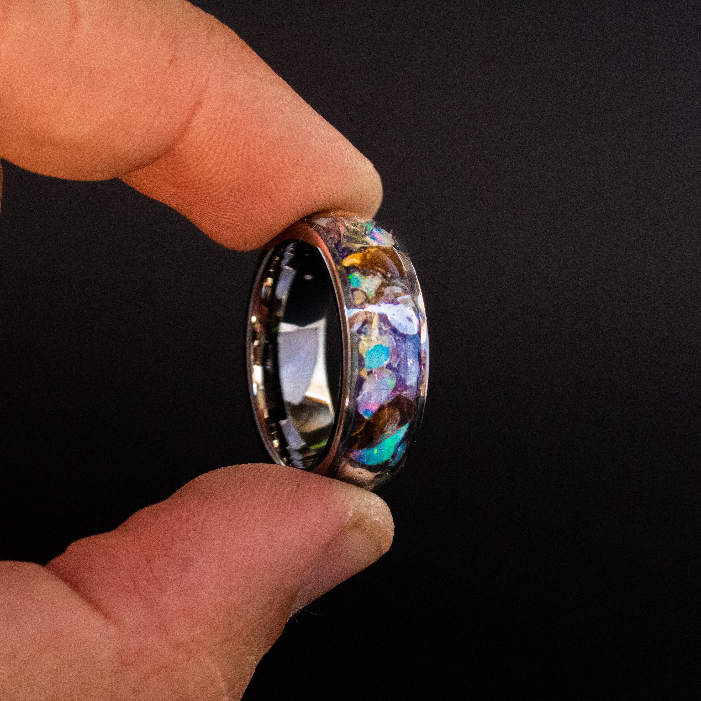 Detail shot of the Premium Rex ring showing large authentic T-Rex bone pieces, meteorite chunks, and Ethiopian Opal fire play on wide channel tungsten band