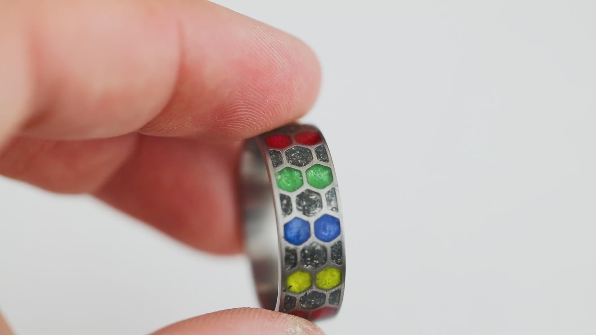 360 degree product view of the Cosmic Infinity ring showing Campo del Cielo meteorite dust and alternating red blue yellow green resin cells in titanium honeycomb band