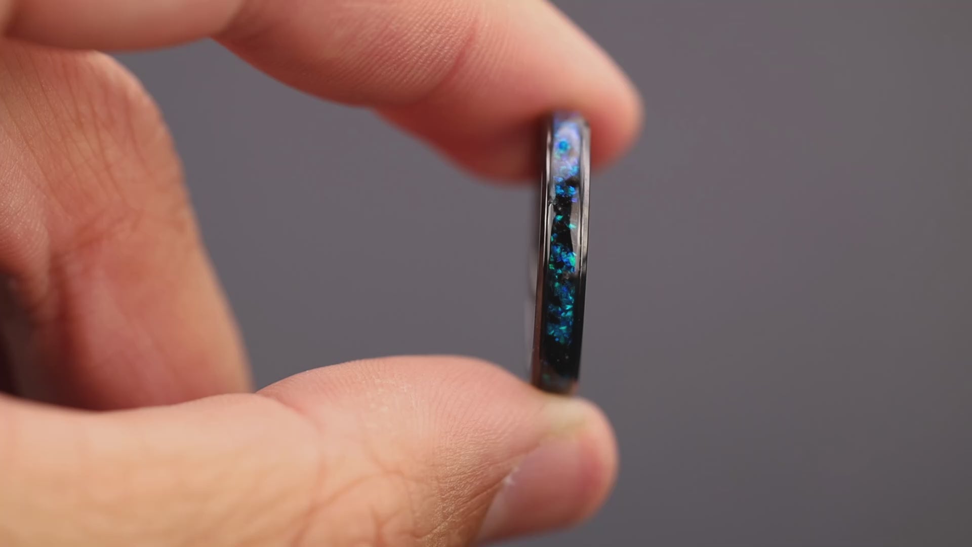 360 degree product view of the Blue Megalodon Slim ring showing Megalodon tooth fragments shifting through blue opal inlay transitioning to blue glow in the dark on 4mm beveled black ceramic band