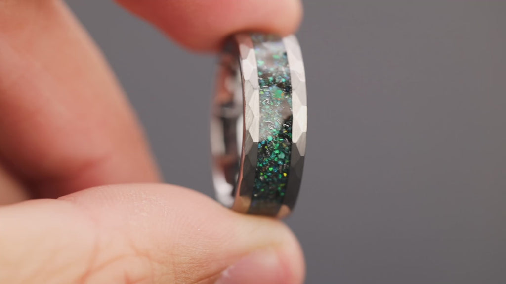 360 degree product view of the Hammered Megalodon Glow ring showing Megalodon tooth and Campo del Cielo meteorite shifting through blue and green opal inlay transitioning to blue glow in the dark on hammered tungsten band