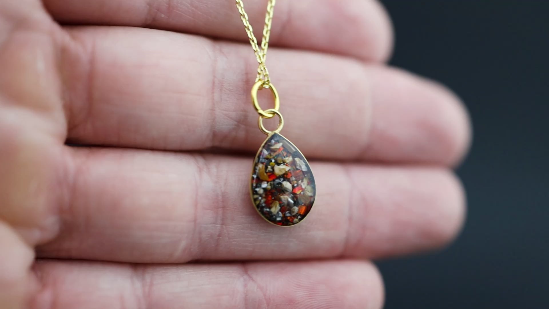 Video of the Ruby Raptor Drop teardrop pendant necklace in gold-plated sterling silver featuring Campo Del Cielo meteorite, red opal, and velociraptor fossil inlay