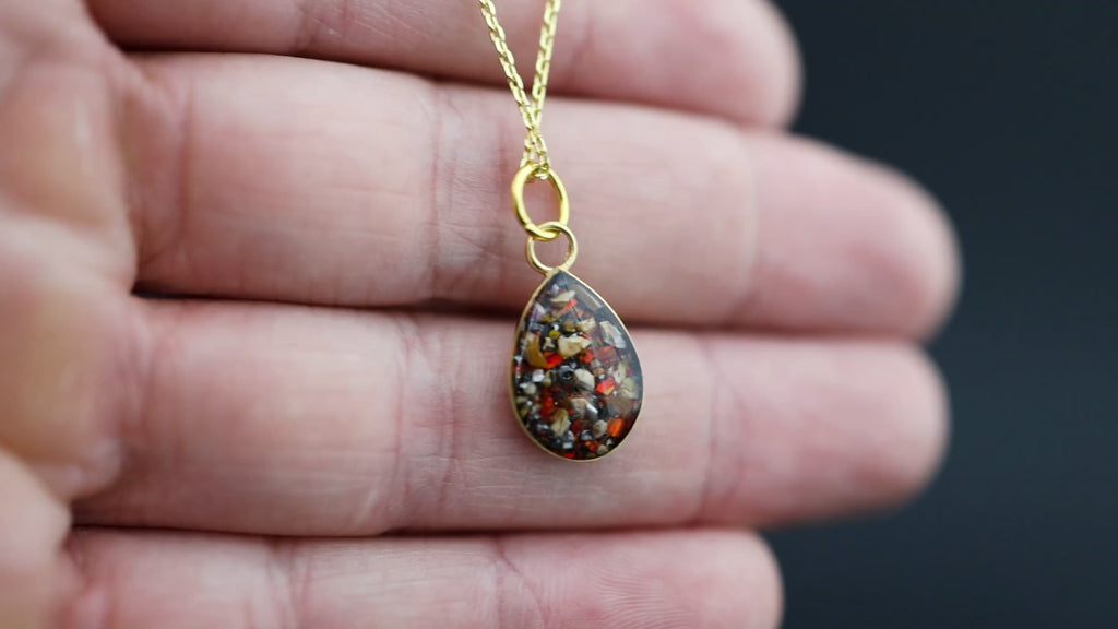 Video of the Ruby Raptor Drop teardrop pendant necklace in gold-plated sterling silver featuring Campo Del Cielo meteorite, red opal, and velociraptor fossil inlay