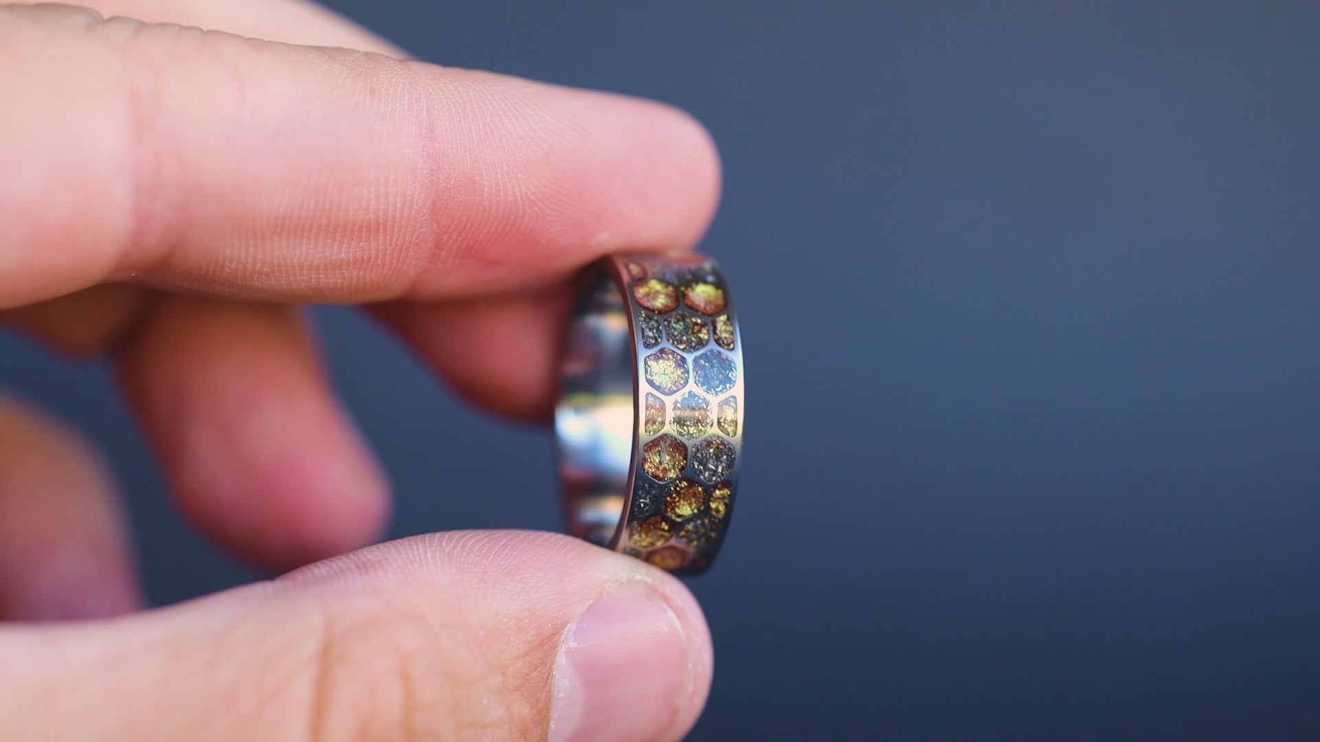 Rotating view of the Golden Honeycomb titanium ring showing gold resin and meteorite inlay catching the light across every hexagonal cell.