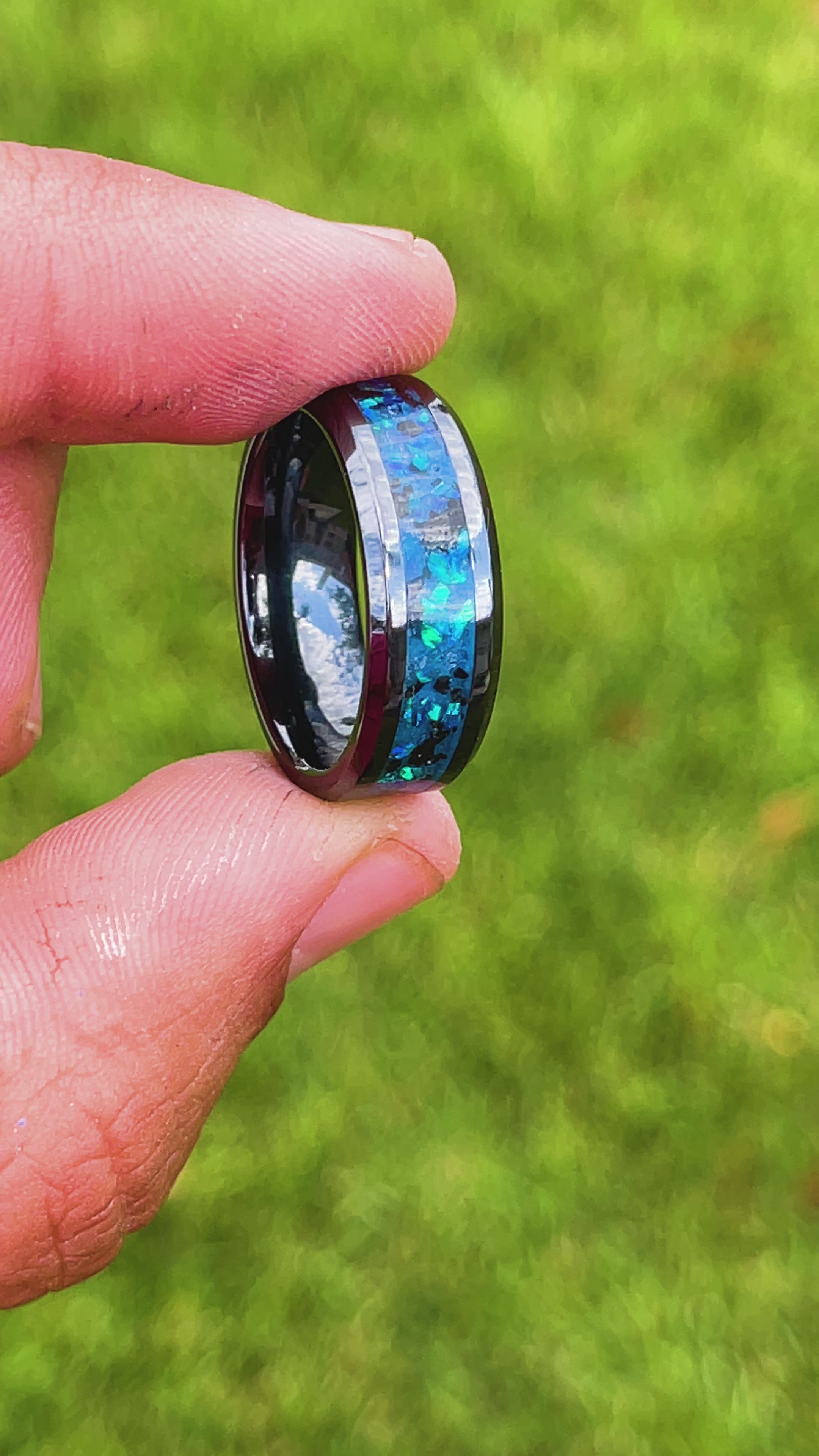 360 degree product view of the Blue Megalodon Glow ring showing Megalodon tooth fragments shifting through blue opal inlay transitioning to blue glow in the dark on beveled black ceramic band