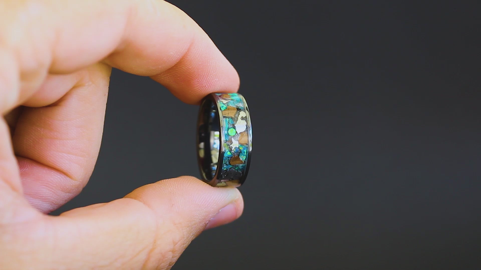 360 degree product view of the Epic Rex ring showing large T-Rex bone pieces and Campo del Cielo meteorite chunks shifting through blue and green opal inlay on 8mm wide channel tungsten band