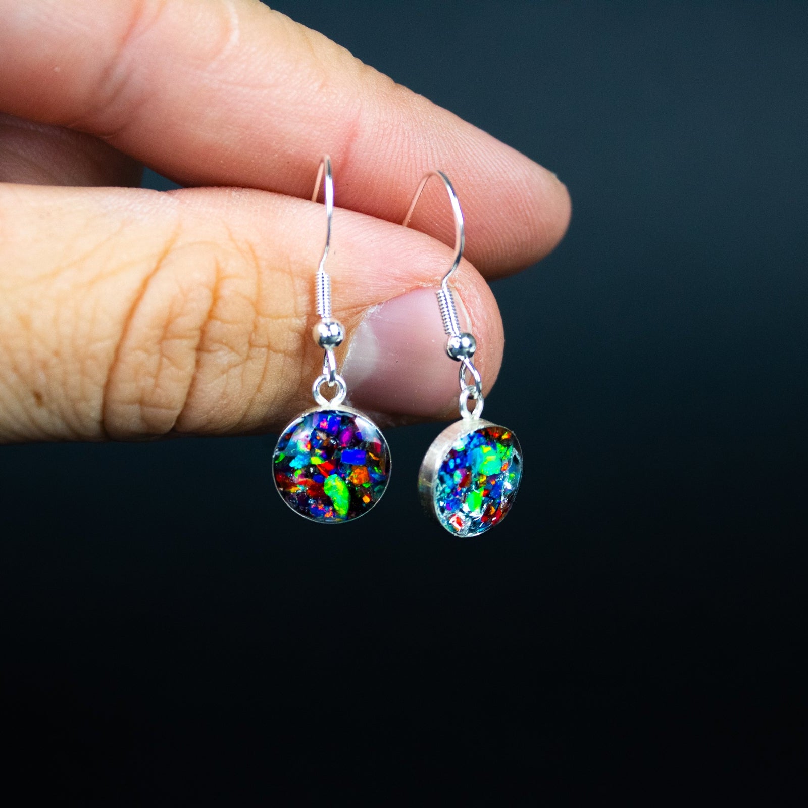 Close-up of the Rainbow Dinosaur Dangle rainbow opal drop earrings showing Campo Del Cielo meteorite and real dinosaur bone set with a full rainbow of colored opals