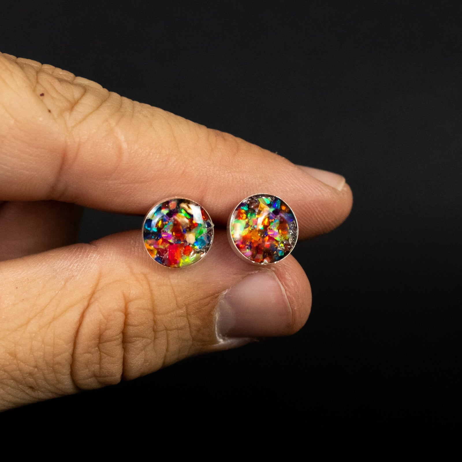 Close-up of the Rainbow Dinosaur Studs rainbow opal earrings showing Campo Del Cielo meteorite and real dinosaur bone set with a full rainbow of colored opals