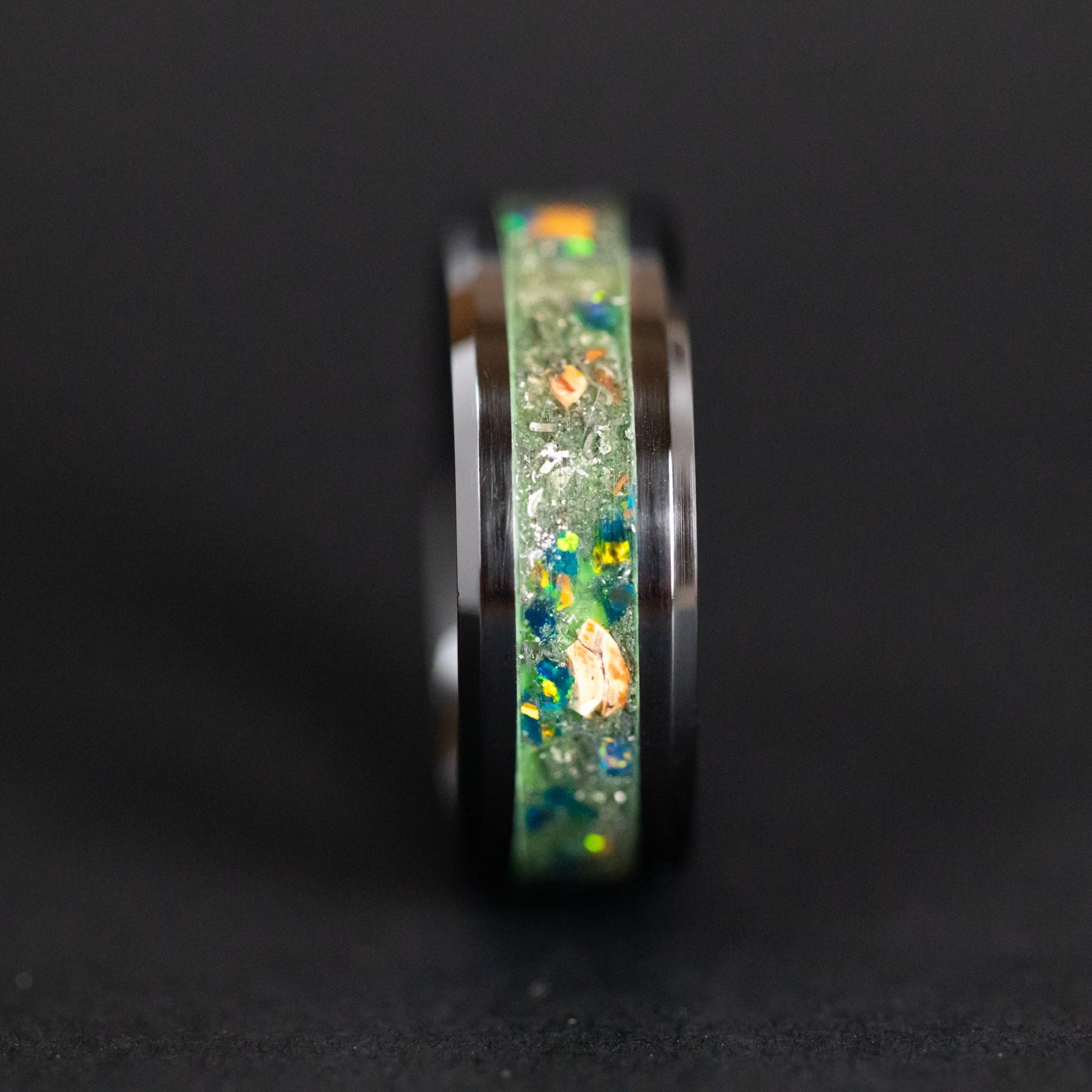 Raptor Venom ring glowing green in total darkness showing Velociraptor bone and meteorite suspended in electric green glow in the dark inlay