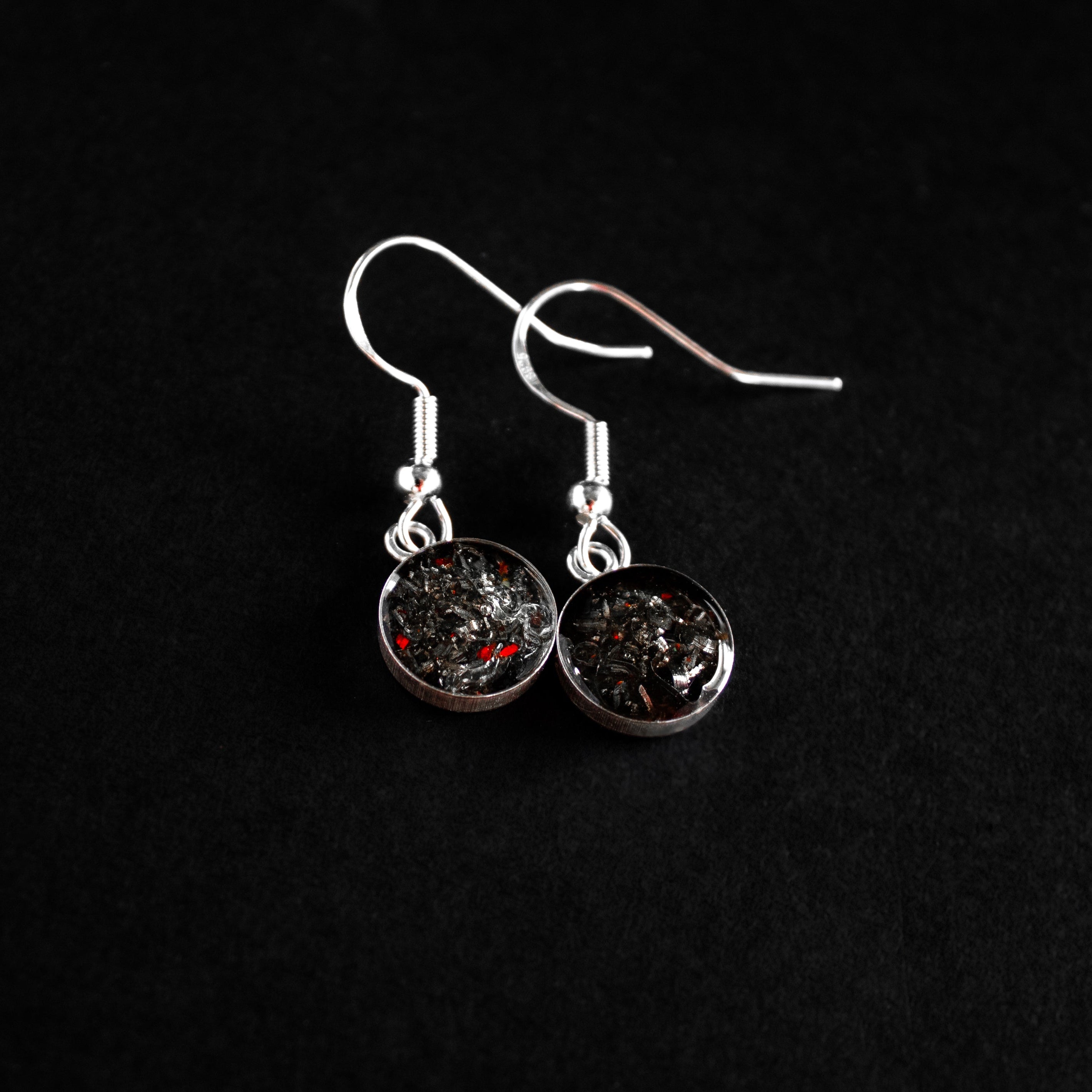 Close-up of the Red Spark Dangle drop earrings showing Campo Del Cielo iron meteorite accented by a spark of vivid red opal in sterling silver