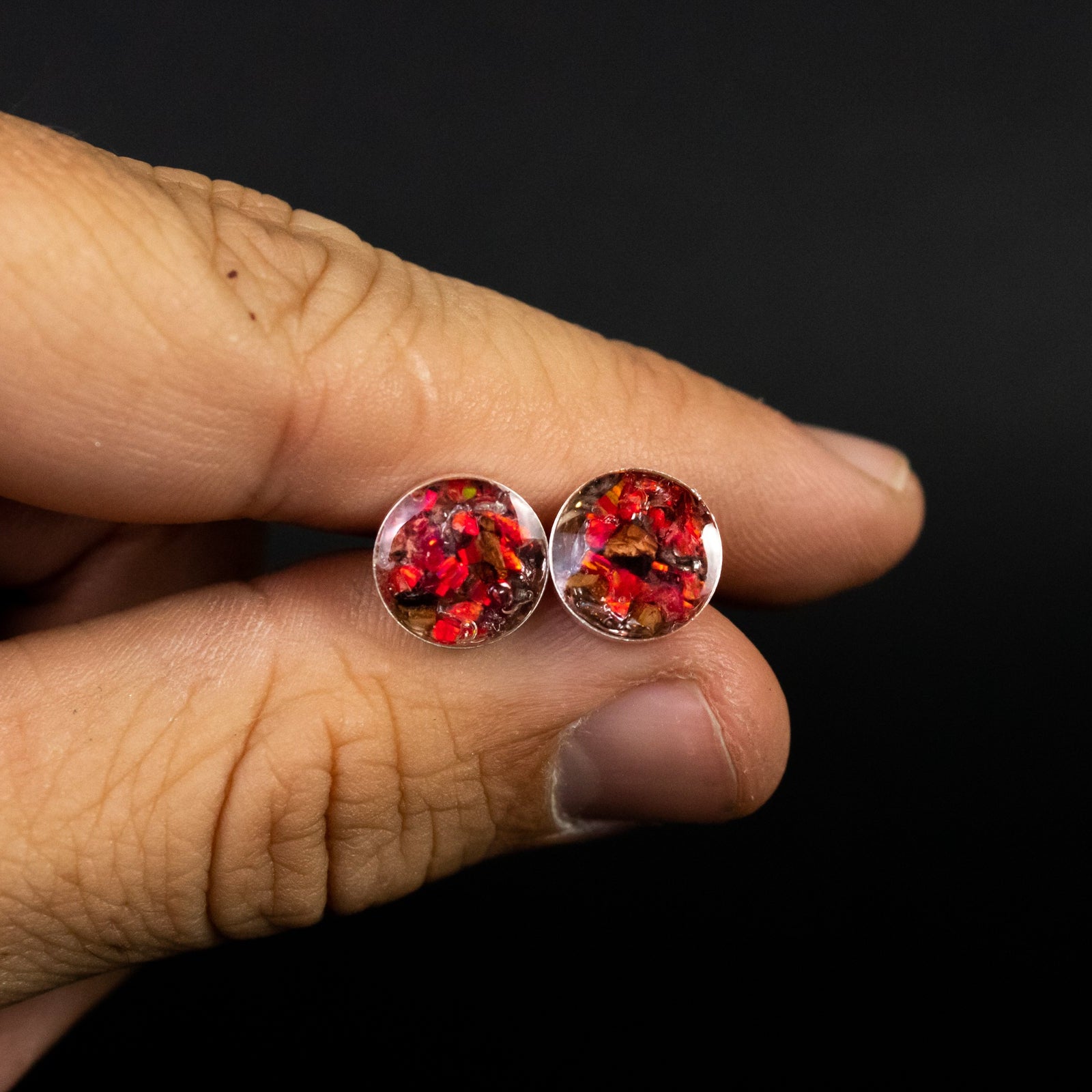 Close-up of the Ruby Red TRex dinosaur earrings showing Campo Del Cielo iron meteorite, real T-Rex bone, and ruby red opal in each stud