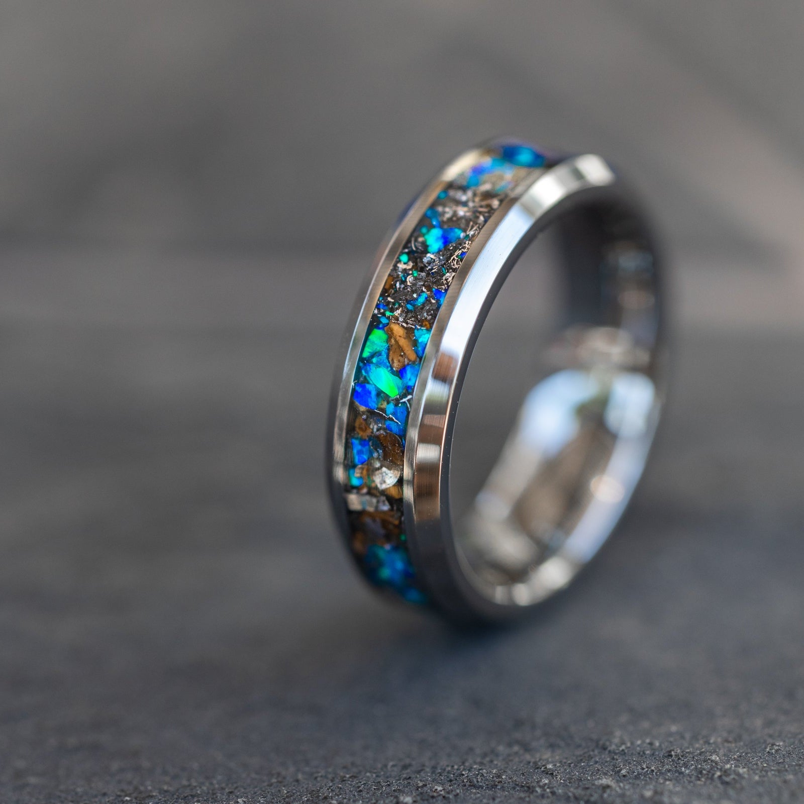 Close up of genuine T-Rex fossil and Campo del Cielo meteorite shavings suspended in blue opal inlay on beveled tungsten ring