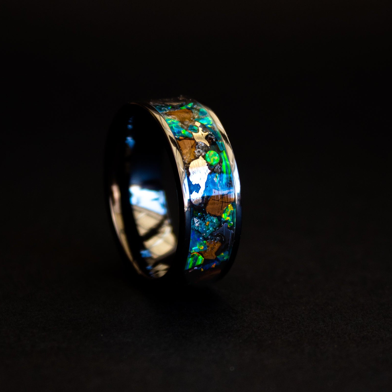 Close up of large genuine T-Rex fossil pieces and Campo del Cielo meteorite chunks surrounded by blue and green opal inlay on wide channel tungsten ring