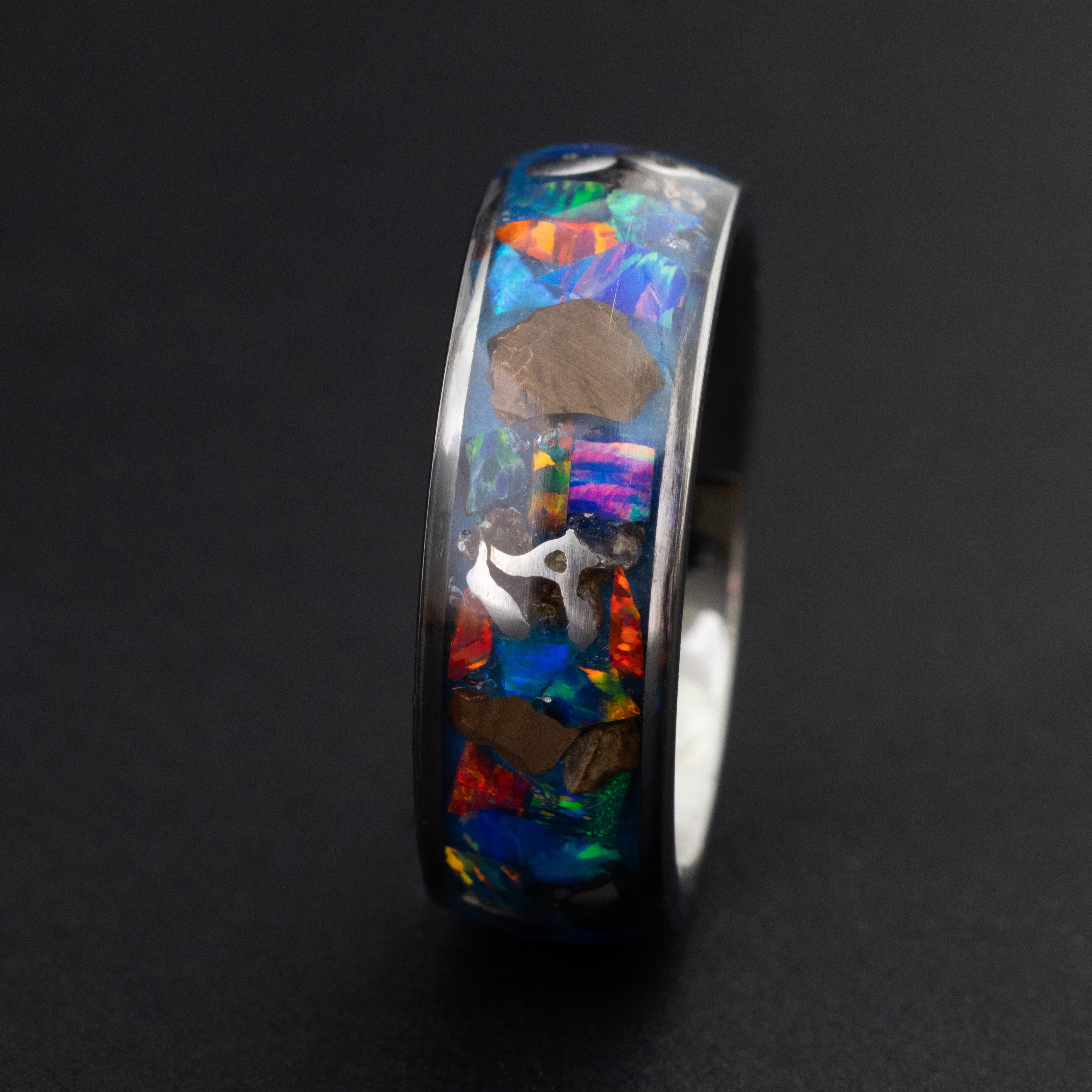 Close up of large genuine T-Rex fossil pieces and Campo del Cielo meteorite chunks surrounded by multi-color opal mosaic on wide channel tungsten ring