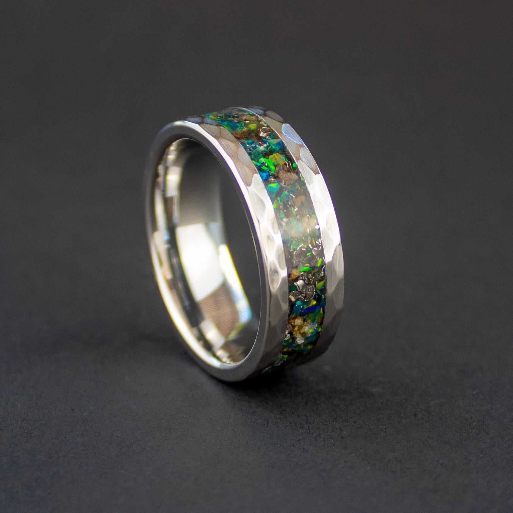 Close up of genuine T-Rex fossil and Campo del Cielo meteorite shavings suspended in green opal inlay on hammered tungsten ring