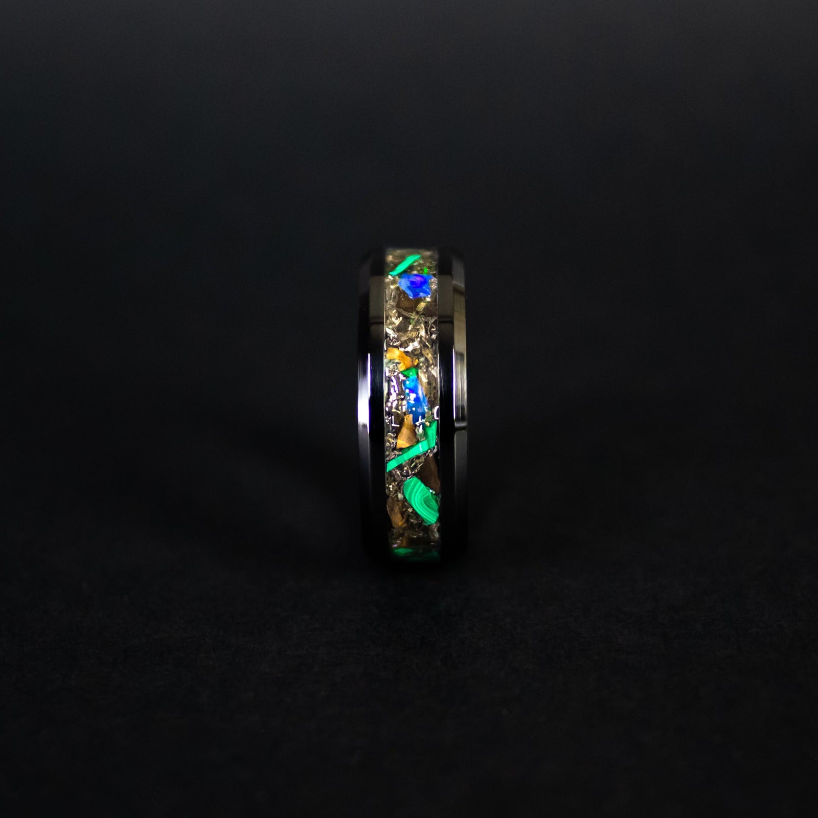 Close up of genuine T-Rex fossil, Campo del Cielo meteorite shavings, natural malachite, and Ethiopian Opal pieces on beveled black ceramic ring