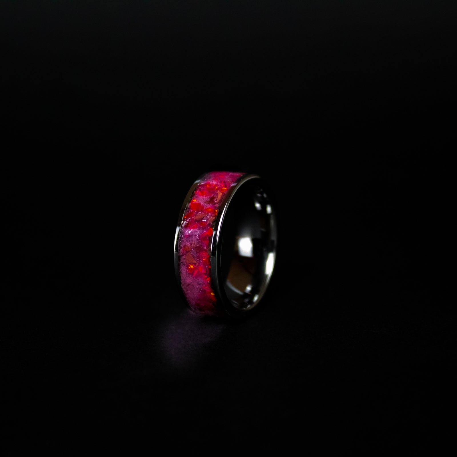 Close up of genuine T-Rex fossil and Campo del Cielo meteorite shavings suspended in red opal inlay on wide channel tungsten ring