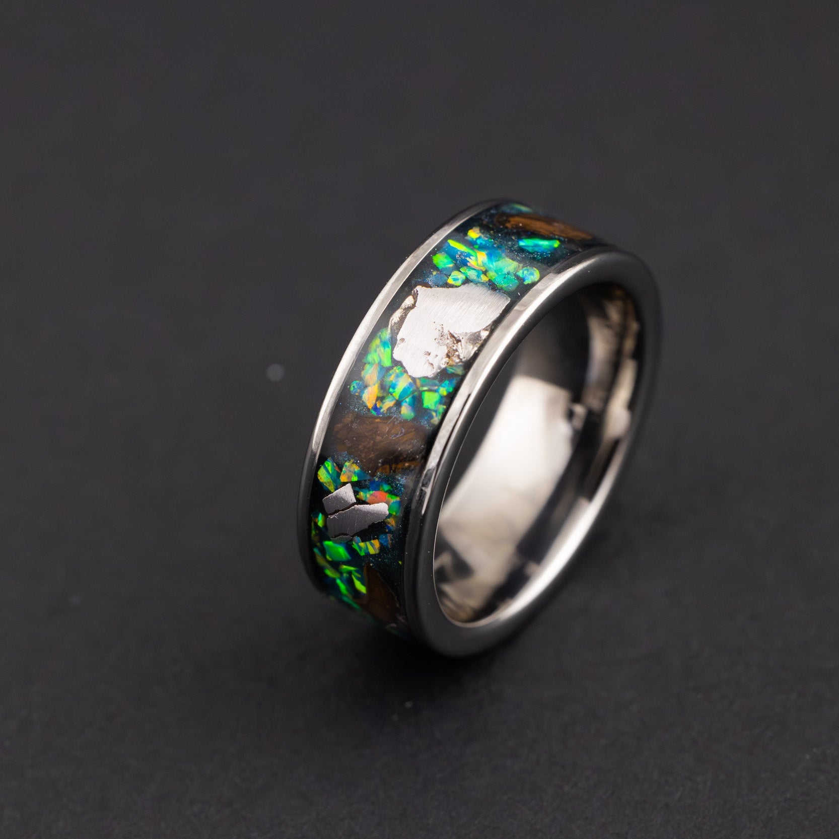Close up of large genuine Triceratops fossil pieces and Campo del Cielo meteorite chunks surrounded by green opal inlay on wide channel tungsten ring