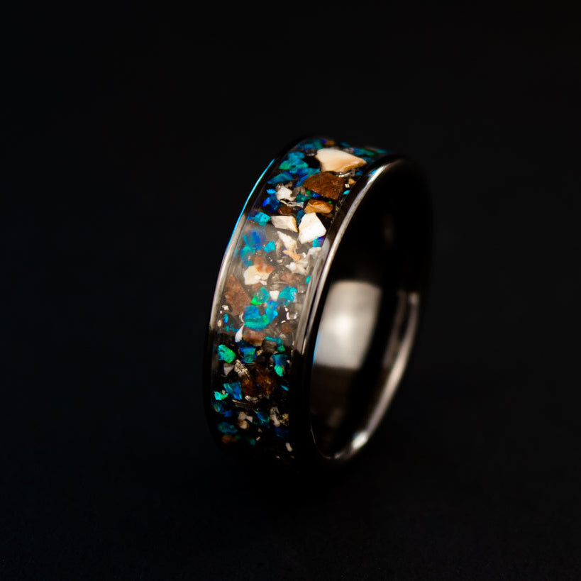 Handcrafted 8mm wide channel black ceramic mens wedding band with authentic Mosasaur bone, Dinosaur Gembone, and Campo del Cielo meteorite in blue opal inlay made in California