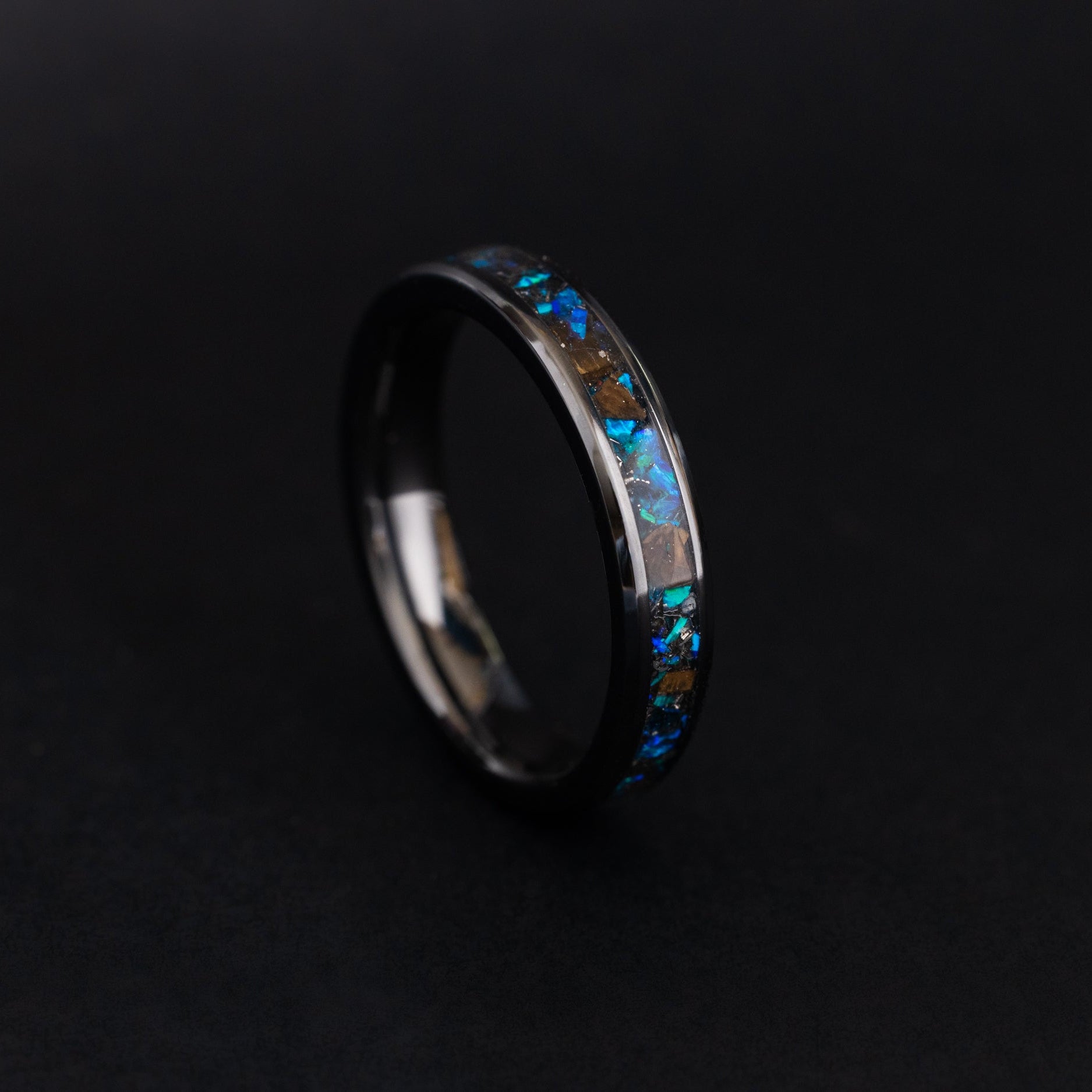 Handcrafted 4mm black ceramic wedding band featuring prehistoric T-Rex bone and cobalt blue opal.