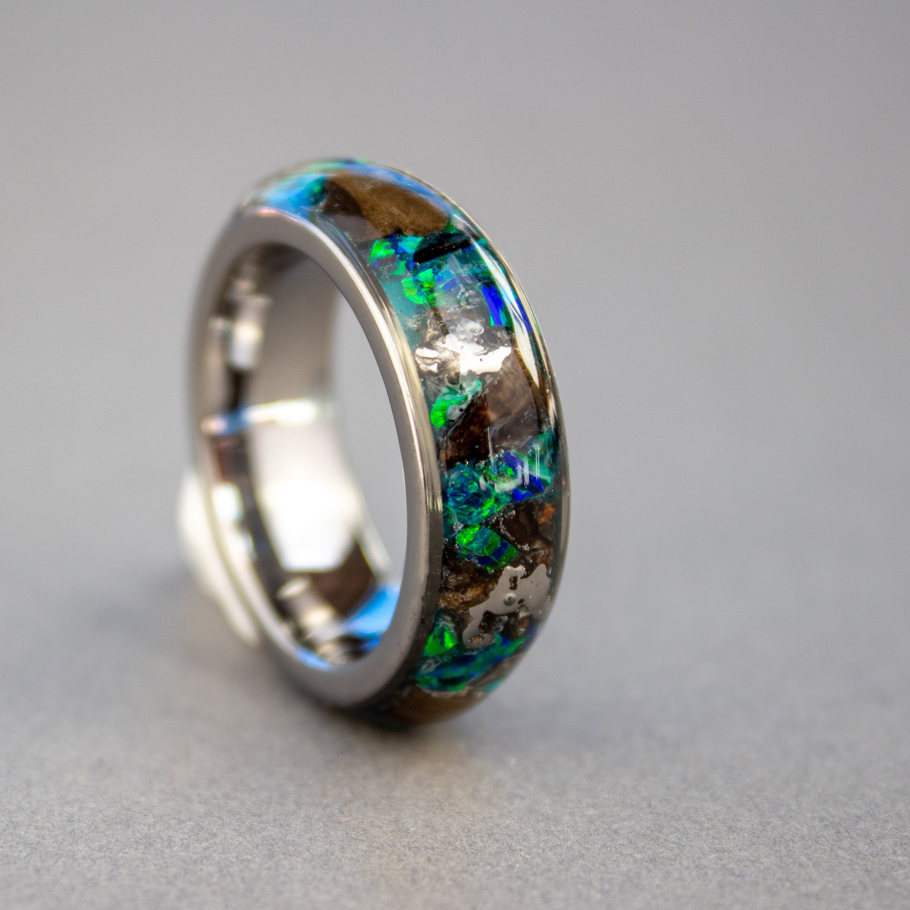 Handcrafted 8mm wide channel tungsten mens wedding band with large authentic T-Rex bone and Campo del Cielo meteorite pieces in blue green opal blue glow inlay made in California