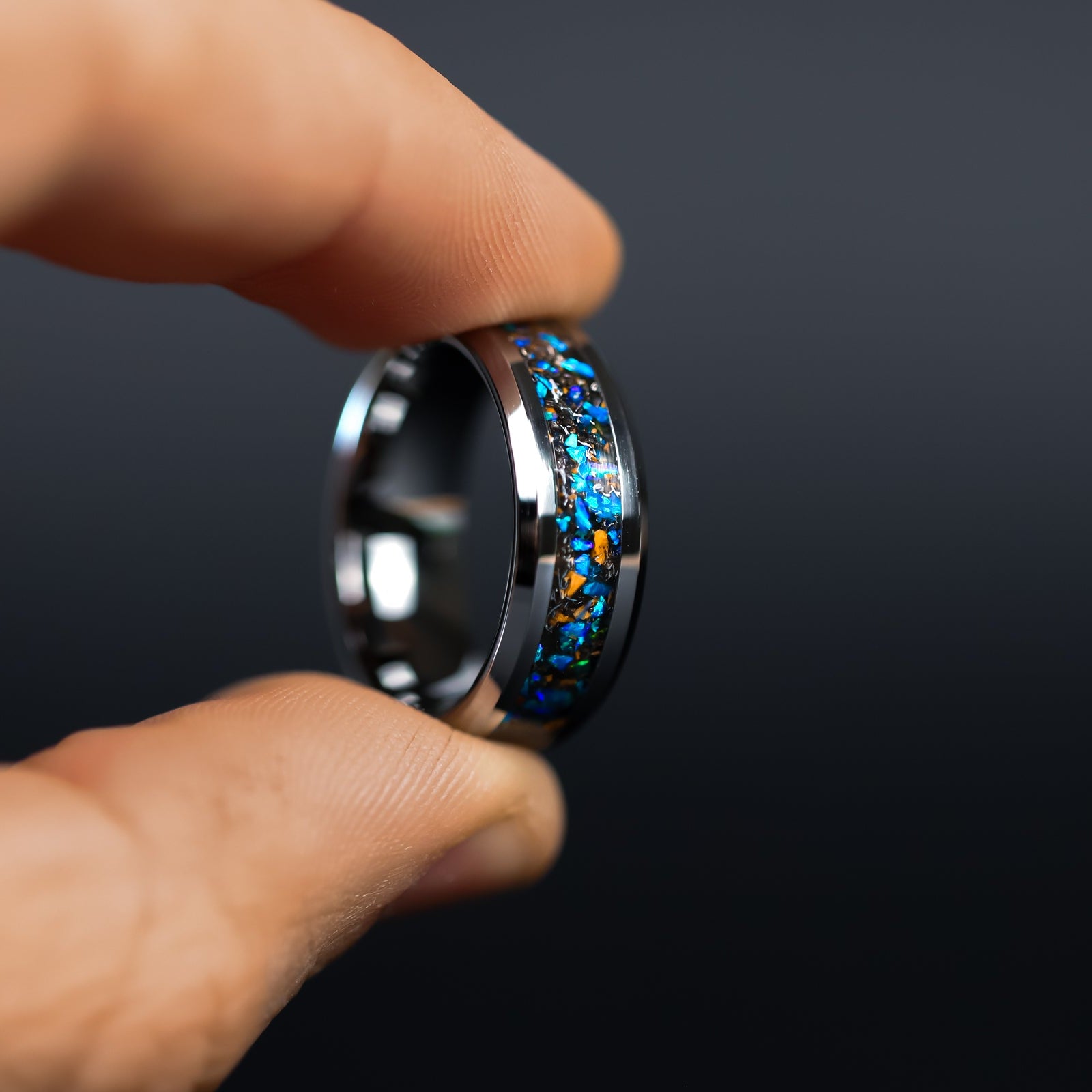 Close up of genuine Velociraptor fossil and Campo del Cielo meteorite shavings suspended in blue opal inlay on beveled tungsten ring