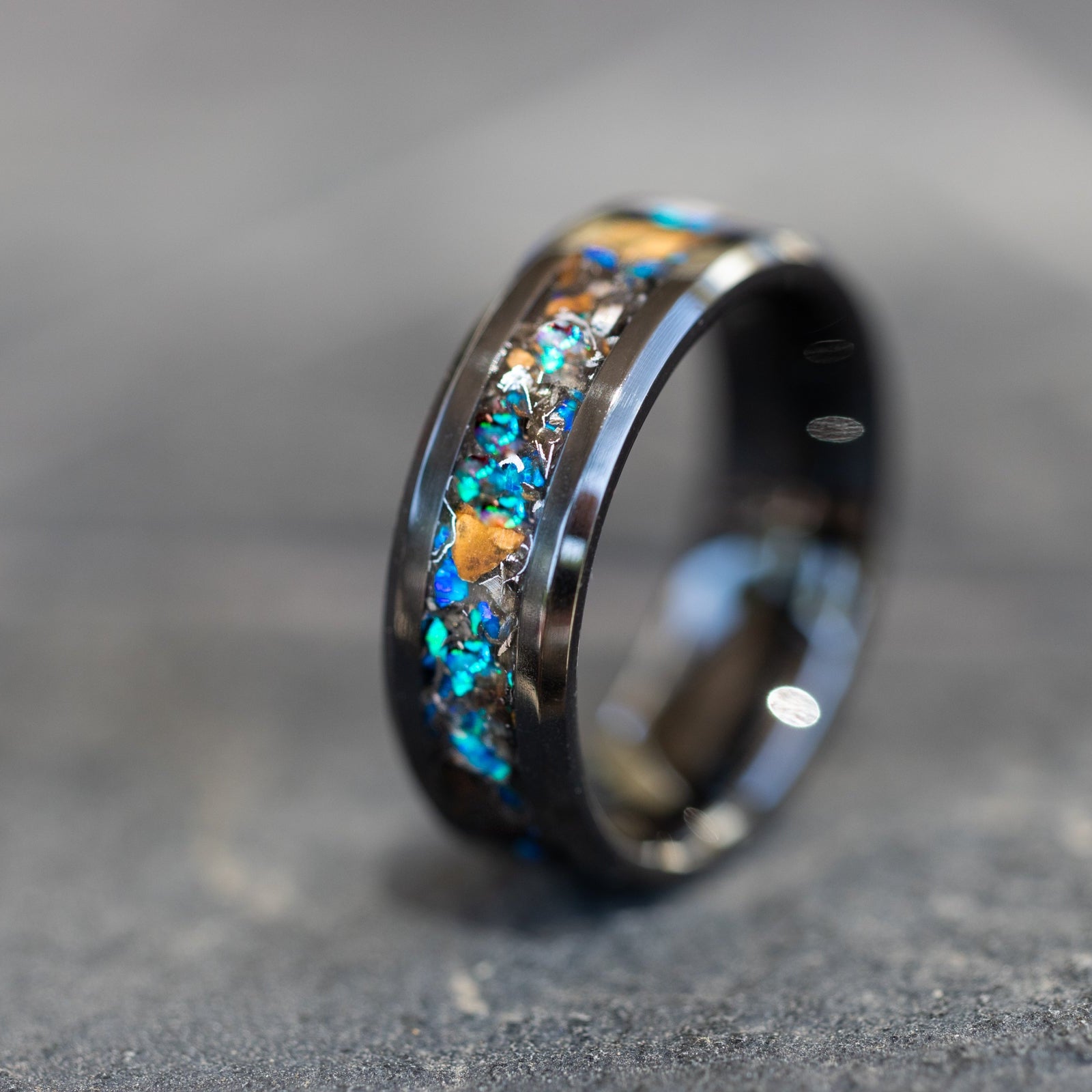 Close up of genuine Velociraptor fossil and Campo del Cielo meteorite shavings suspended in blue opal inlay on beveled ceramic ring
