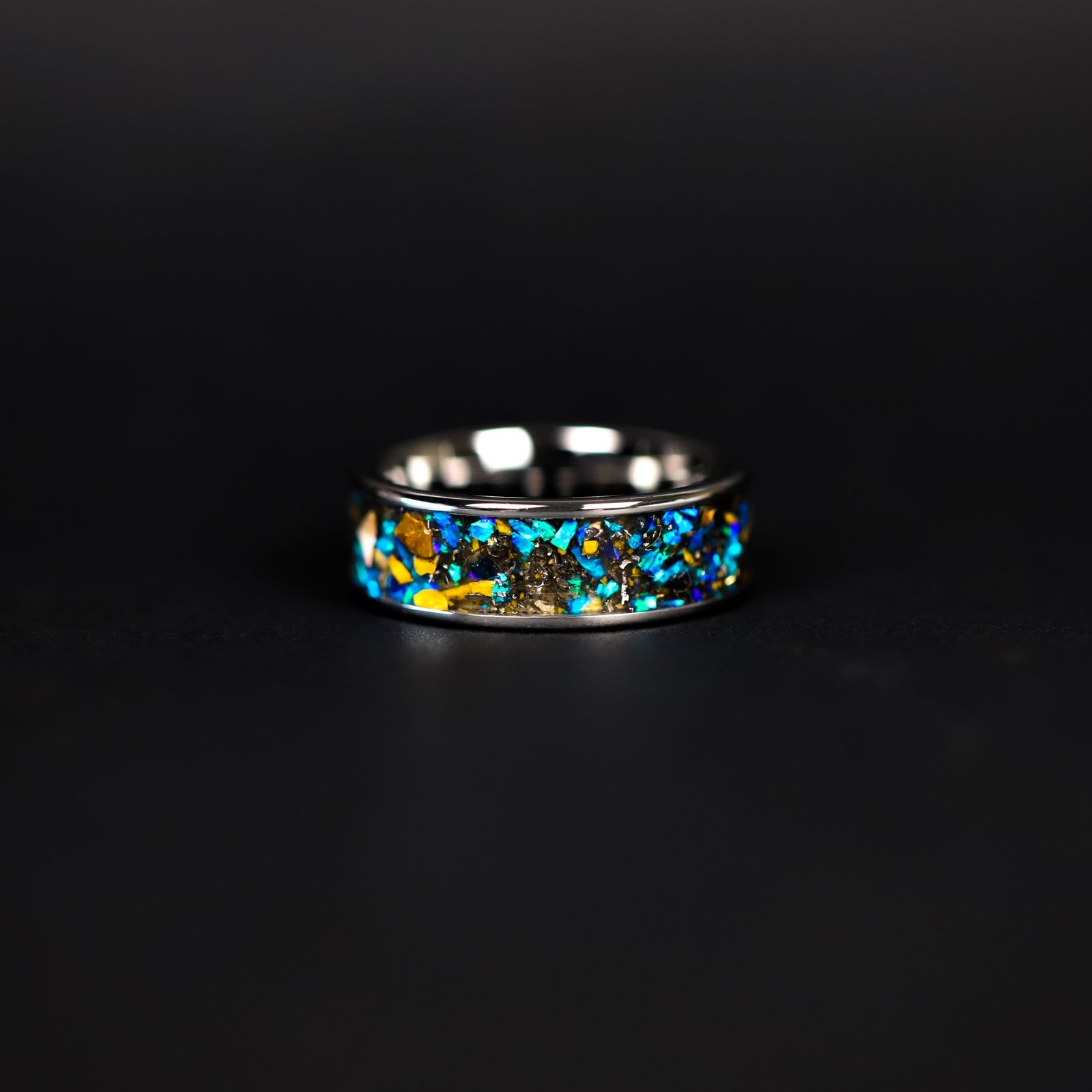 Close up of genuine Velociraptor fossil and Campo del Cielo meteorite shavings suspended in blue opal inlay on wide channel tungsten ring