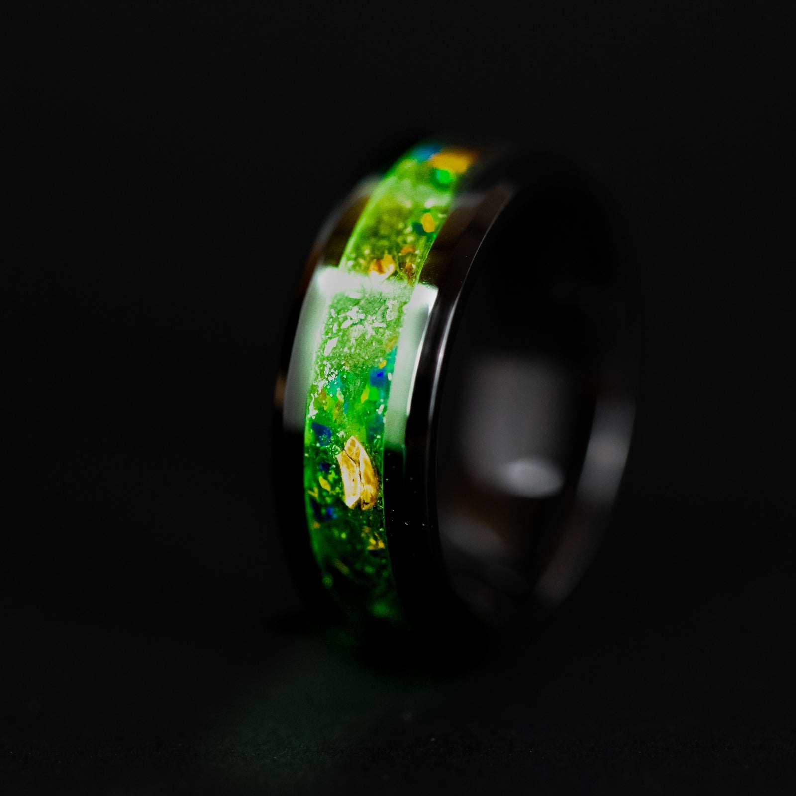 Close up of genuine Velociraptor fossil and Campo del Cielo meteorite shavings suspended in green opal inlay on beveled black ceramic ring