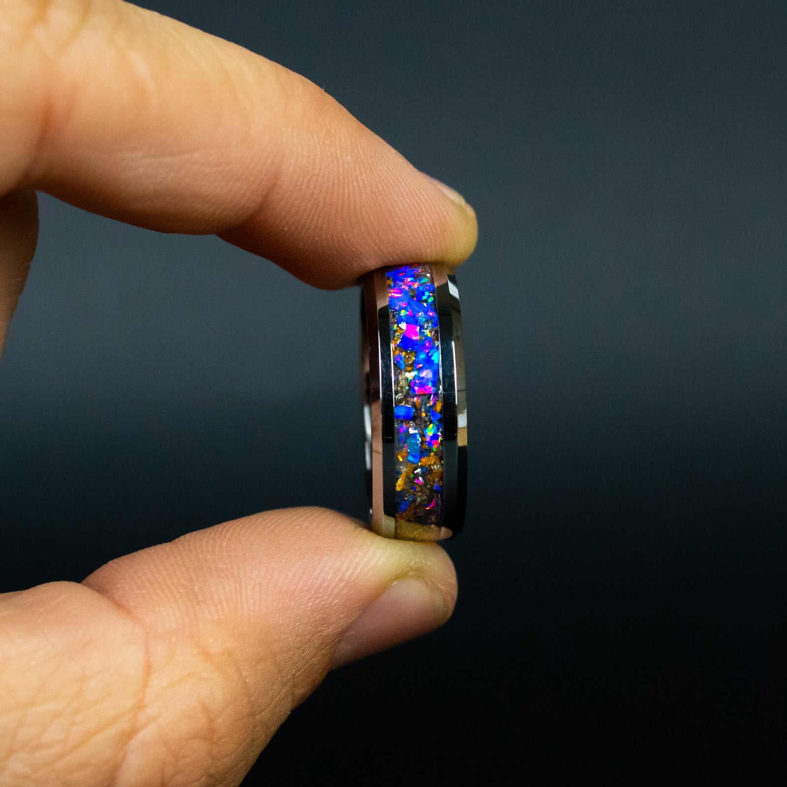 Close up of genuine Velociraptor fossil and Campo del Cielo meteorite shavings suspended in midnight opal inlay on beveled tungsten ring