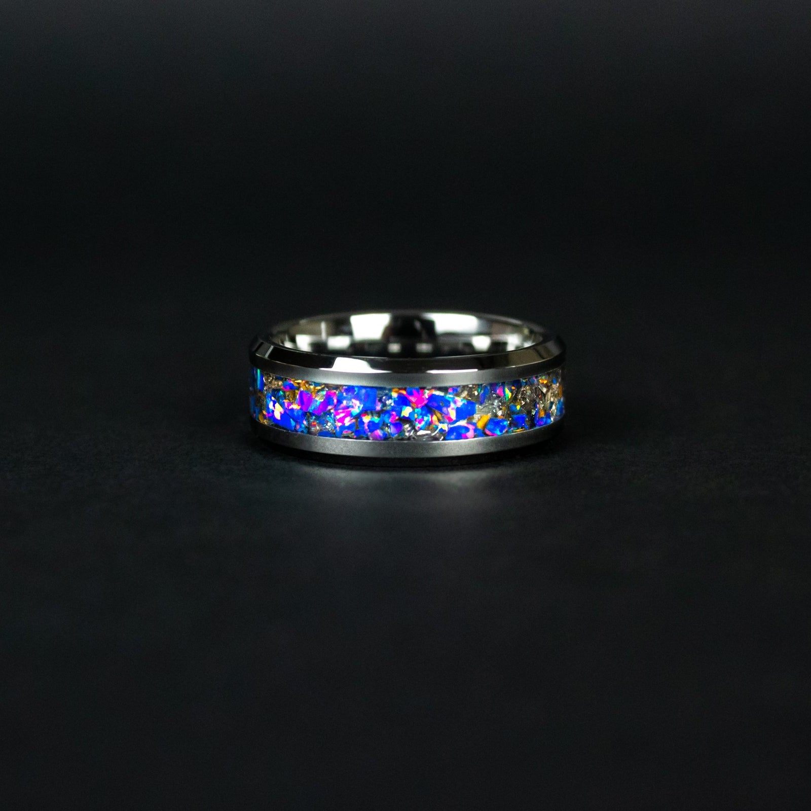Detail shot of the Velociraptor Midnight ring showing authentic Velociraptor bone fragments and meteorite shavings catching light through midnight blue purple opal inlay